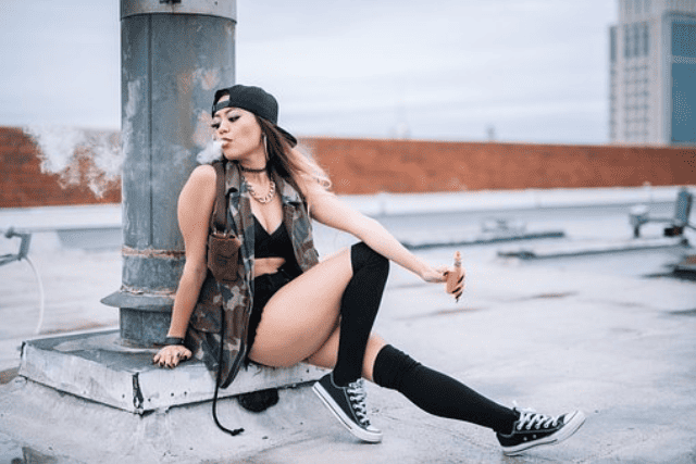 A young woman vaping by the side of the road