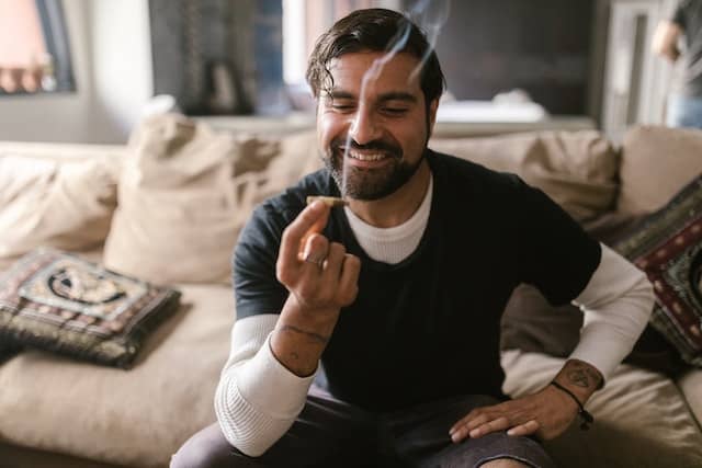 a guy holding a lit marijuana stick