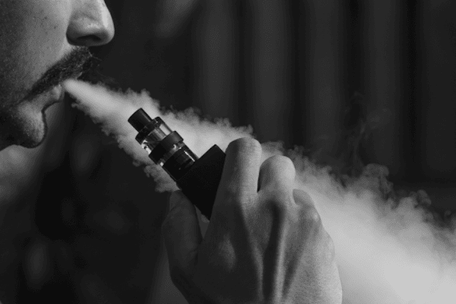guy puffing vape - in black and white